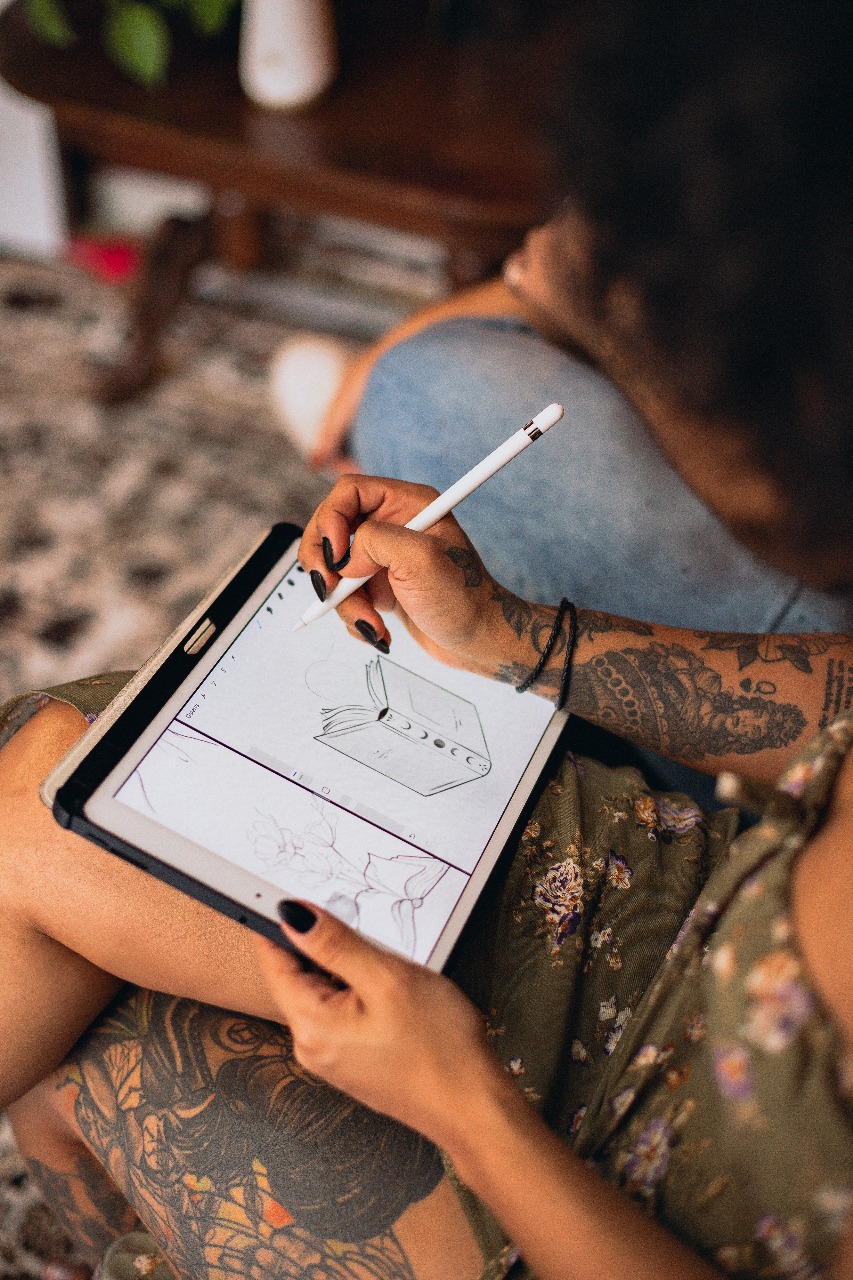 Tatuadora desenhando a arte no iPad junto com a cliente